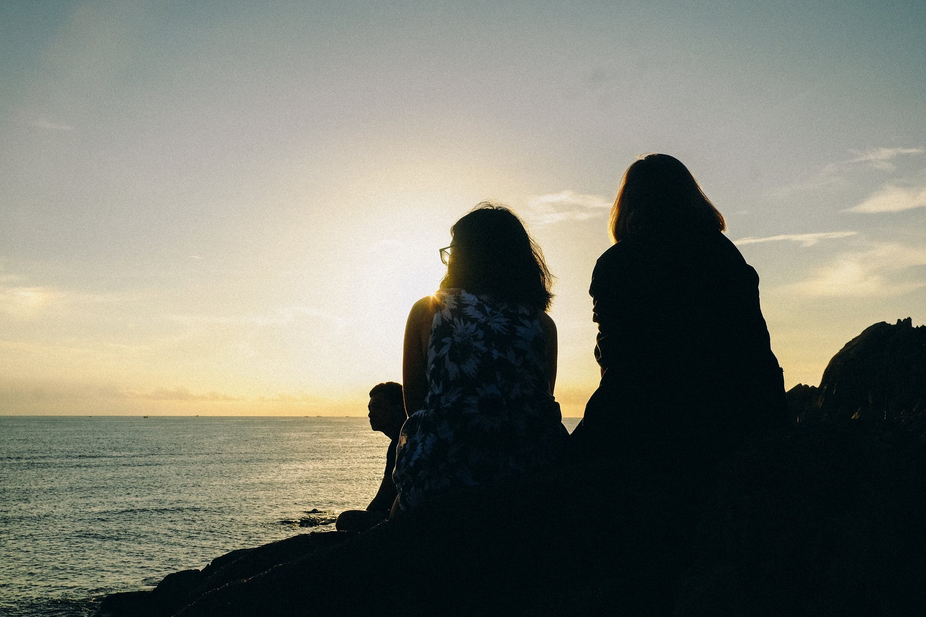 silhouette of two women facing body of water